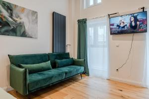 Modern Stay Unique Berlin في برلين: غرفة معيشة مع أريكة خضراء وتلفزيون بشاشة مسطحة