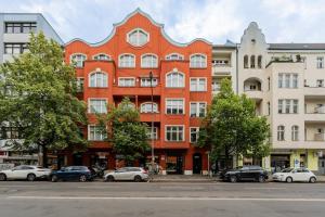 Modern Stay Unique Berlin في برلين: مبنى برتقالي فيه سيارات تقف امامه