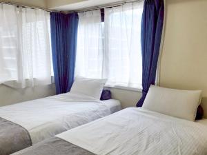 a bedroom with two beds and a window with blue curtains at ダイアパレス大手門 in Kanazawa