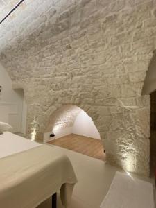 a room with a stone wall and a table at Suite Prima Pietra with mini pool in Ostuni