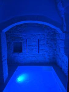 a blue light in a room with a stone wall at Suite Prima Pietra with mini pool in Ostuni +3 photos