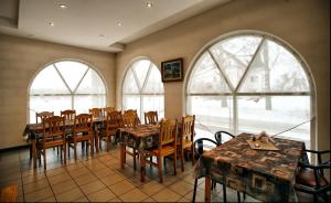 een eetkamer met tafels, stoelen en ramen bij Oškrogs in Ķegums