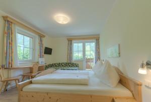 Schlafzimmer mit einem Bett, einem Stuhl und Fenstern in der Unterkunft Haus am Hammerrain in Flachau
