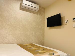 Habitación con cama y TV en la pared. en I GO Hotel, en Tokio