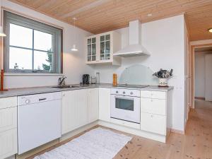 a kitchen with white cabinets and a sink and a window at 6 person holiday home in Læsø in Læsø +16 photos