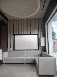 a living room with a white couch and a large window at Hotel Tanishka Inn in Mathura +12 photos