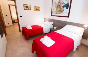 a hotel room with two beds with red sheets at Appartamento La Cittadella in Piombino