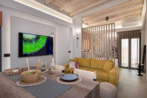 a living room with a couch and a tv on a wall at Seaera Studio with Sea View in Stavros