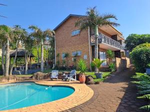 a house with a swimming pool in front of a house at Beachfront Cabanas in Amanzimtoti
