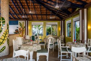a restaurant with white tables and chairs and windows at Casa Baga in Baga