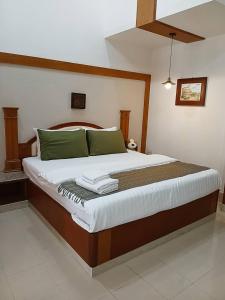 a bedroom with a large bed with green pillows at Rosie Garden & Home in Ban Bung