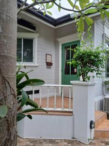 a house with a porch with a green door at Rosie Garden & Home in Ban Bung