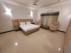 a bedroom with a bed and two chairs in it at Glasswings fx 147 in Islamabad