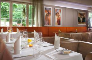 ein Restaurant mit weißen Tischen, Stühlen und Fenstern in der Unterkunft Hotel Reza in Franzensbad