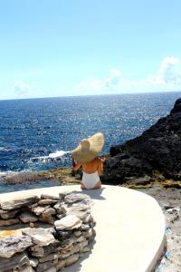 Una donna con un cappello seduta su un sentiero che guarda l'oceano di Ocean Tally a Upper Bogue