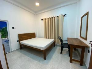 a bedroom with a bed and a table and a chair at Crystal house in Weligama