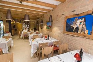 a restaurant with white tables and chairs and a wall at LE RIVE Guest House La Ciosà in Chioggia