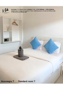 two white beds with blue pillows in a room at Koh Larn White House in Ko Larn