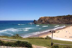 a beach with a bunch of people in the ocean at Apartamentos Cavaco in Odeceixe
