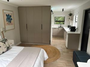 a bedroom with a white bed and a kitchen at Suburban Bliss in Stellenbosch