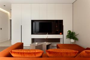 un soggiorno con divani arancioni e TV a schermo piatto di M&M Urban Escape a Arad