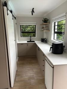 a kitchen with white counters and a sink and a window at Suburban Bliss in Stellenbosch