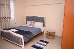 a bedroom with a bed with a gray headboard at Lavender Cute Homes in Thika