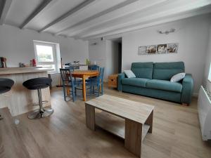 a living room with a green couch and a table at Charmant petit T2 à proximité de Quimper in Ergué-Gabéric