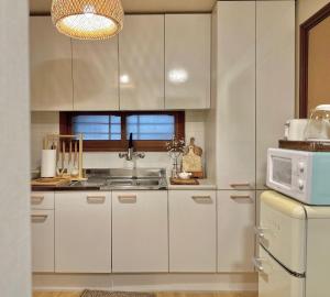 a kitchen with white cabinets and a microwave at Hayoungs House in Seoul
