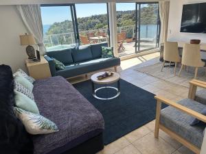 a living room with a couch and a table at Palm Breeze Getaway-Waiheke Island Resort Premium 95m Villa in Waiheke Island