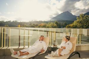 a man and woman sitting in chairs on a balcony at Hotel Lomnica in Tatranská Lomnica