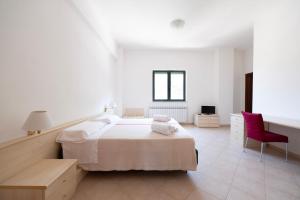 a white bedroom with a bed and a red chair at Heart's Home - La casa degli amici di Monteverde in Monteverde +30 photos