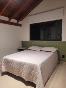 a bedroom with a large white bed with a window at Chalé Alto do Paraíso in Pouso Alegre +16 photos