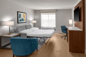 a living room with a couch and a table and chairs at Doubletree By Hilton Owatonna in Owatonna