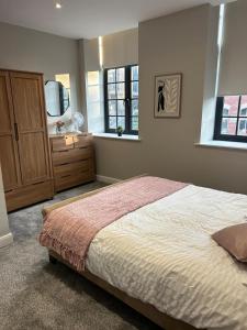a bedroom with a bed and a dresser and two windows at Stylish apartment in Halifax in Halifax