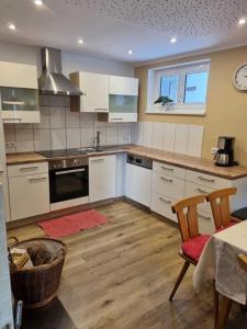 a kitchen with white cabinets and a table with a chair at Ferienhaus Waldklause in Schwarzenberg im Bregenzerwald