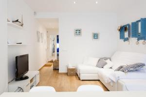 a white living room with a white couch and a tv at Casa Cris Palamos in Palamós