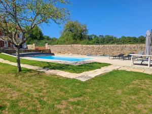 una piscina in un cortile accanto a un muro di pietra di Hébergement Cressia a Cressia