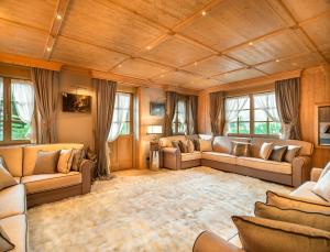 a large living room with couches and windows at Elegant Tablà with Garden R&R in Cortina dʼAmpezzo