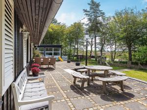 a patio with benches and tables on the side of a house at 19 person holiday home in Løgstør-By Traum in Trend