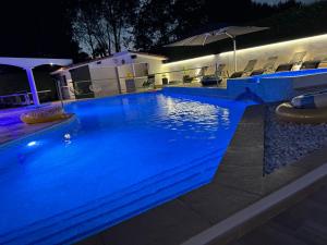 a swimming pool at night with blue lights at Villa Sany:10 Pers Maison 200m2 piscine , jacuzzi in Narrosse