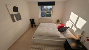 a bedroom with a white bed with a window at am-hoeben in Fehmarn