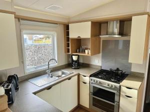a kitchen with a stove and a sink and a window at Mobilheim 2 Seehund 06249 Mücheln Werkstraße 2a in Neu Stöbnitz