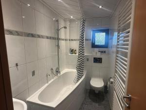 a white bathroom with a tub and a toilet at Zimmervermietung Hirschmann Nürnberg/Messe in Nürnberg