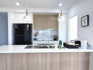 a kitchen with a sink and a black refrigerator at Home Blanc - Brand New, Peaceful & Well Equipped in Ripley +17 photos