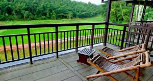 two chairs on a porch with a view of a field at Vayal Veedu - Luxury Farm Villas by the woods in Muthanga +16 photos
