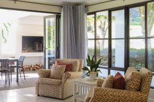 a living room with two chairs and a fireplace at High Season Farm Luxury Cottages in Hermanus