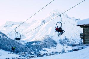 two people riding on a ski lift in the snow at Zug503 Appartement in Lech am Arlberg in Lech am Arlberg +6 photos