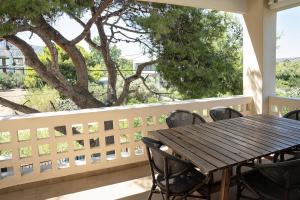 a wooden table and chairs on a balcony with a tree at Comfortable Villa - 2min from the Beach in Porto Rafti