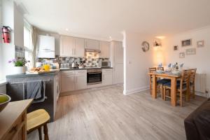 eine Küche mit weißen Schränken und einem Tisch im Zimmer in der Unterkunft Devon Beach Court, sea views of Woolacombe in Woolacombe